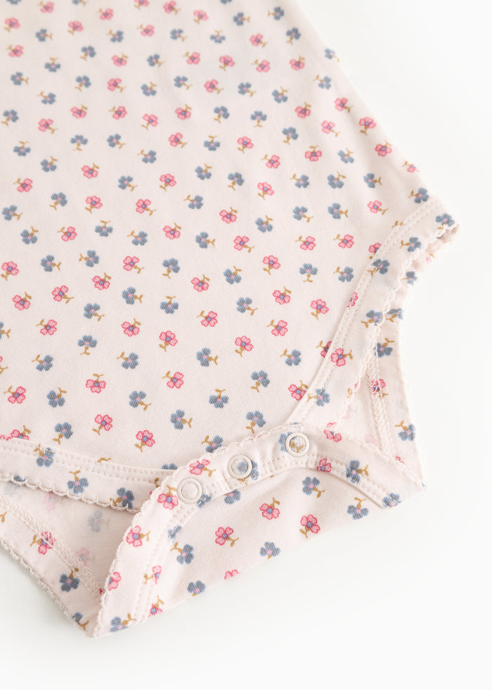 Detalje: lys bodystocking med blomsterprint, knapper og flæsekant ved ben