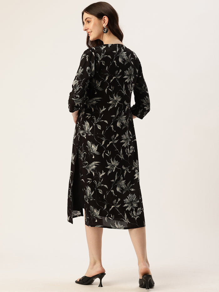 Woman wearing a black dress with floral pattern in a living room setting, Black & Gold Floral Printed Dress, midi dress, dress, women’s western wear, party wear dress, casual wear dress