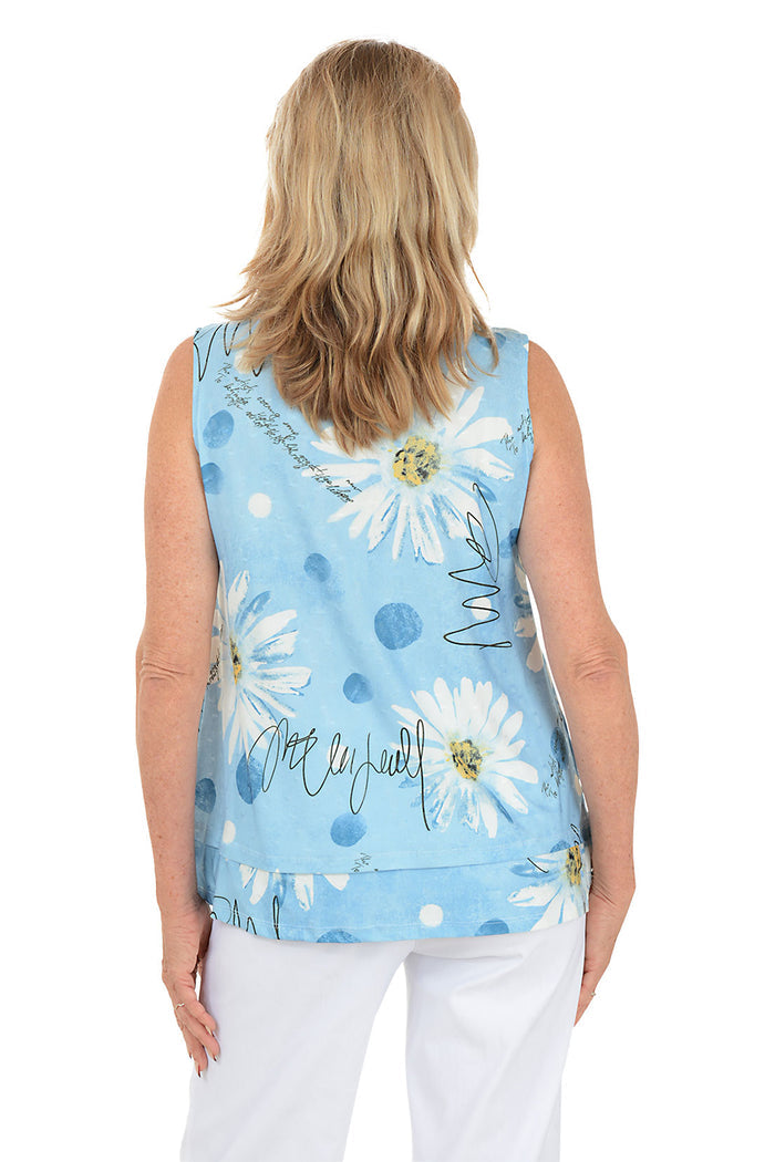 Woman wearing a sleeveless floral blouse with a white background. Back shot.