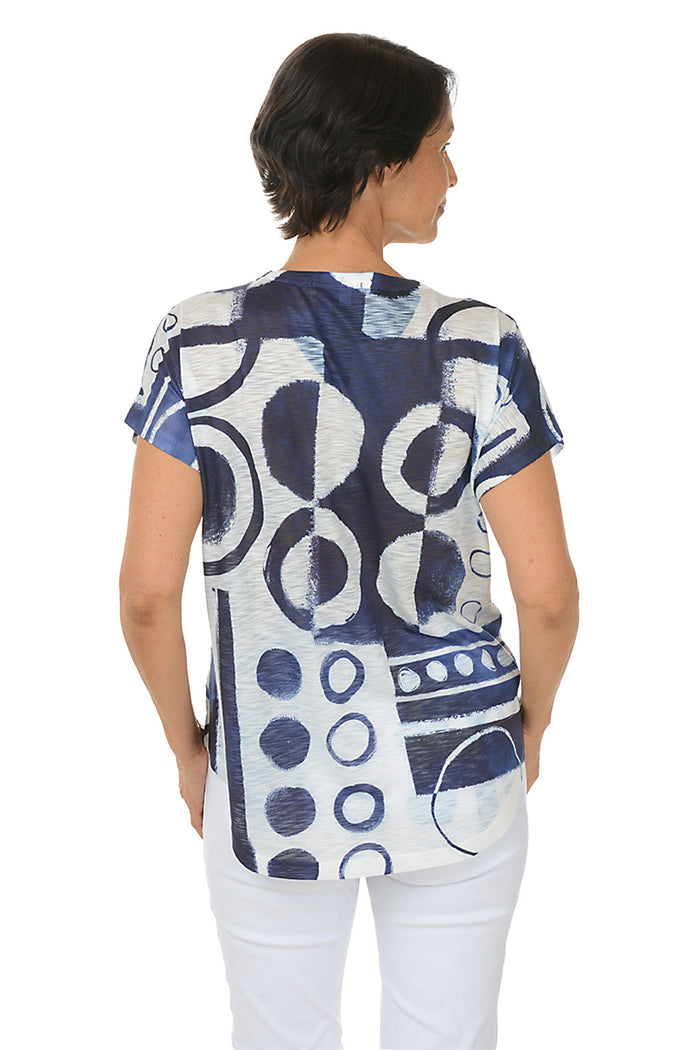A woman wearing a short sleeve navy and white abstract print shirt. Back shot.