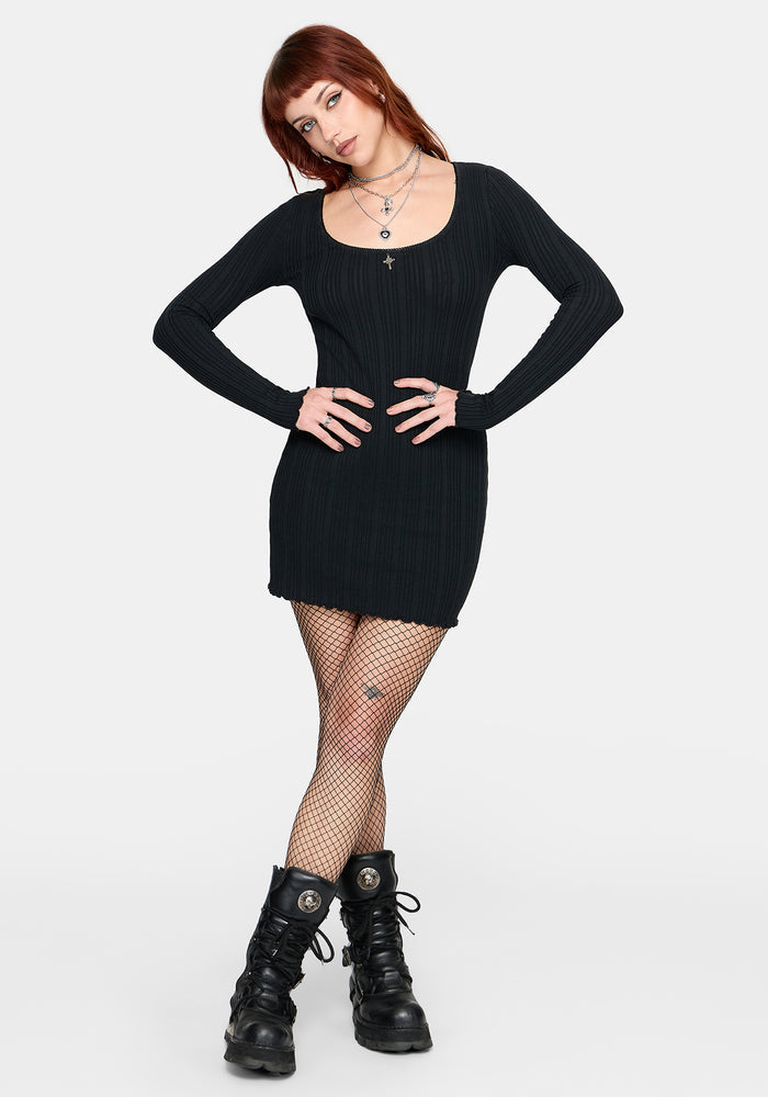 Woman wearing a black mini dress and black boots on a white background
