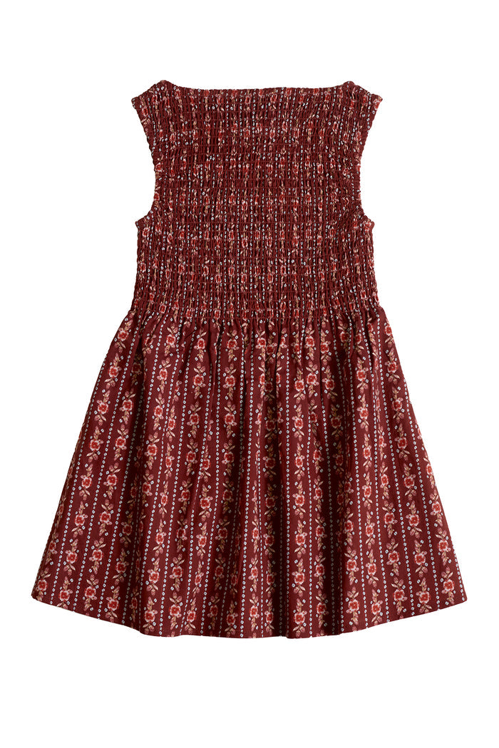 The Mini Ana Dress in Sequoia Felicity Floral by Ivy City Co is sleeveless with a smocked bodice and flared skirt, featuring a light pink and white floral pattern on maroon. Made from lightweight fabric, it’s perfect for warm days.
