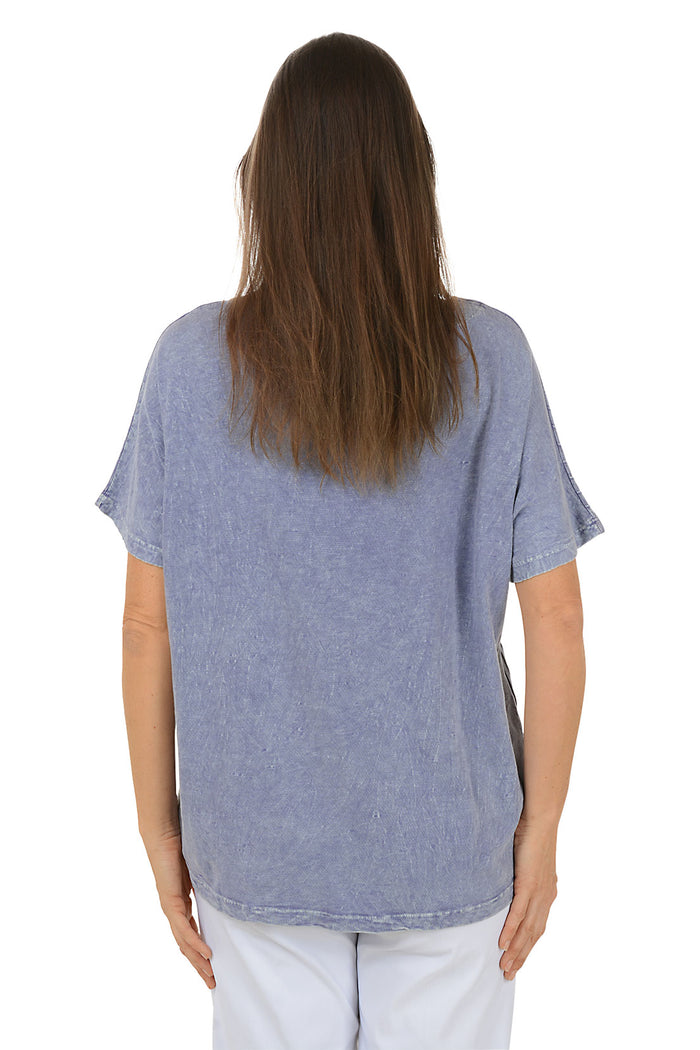 Woman wearing a blue abstract patterned top on a white background. Back shot.
