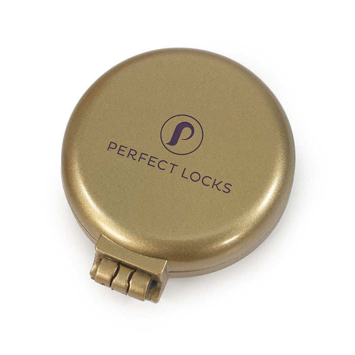 A round, metallic gold Perfect Locks Compact Travel Brush features a stylized P logo on the lid and a bottom clasp for secure closure.