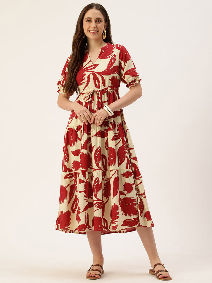 Woman in a red and white floral dress holding a brown handbag, standing next to a small wooden table with flowers on a beige background. Red Floral Printed Puff Sleeves Midi Dress, midi dress, dress, women’s western wear, party wear dress, casual wear dress