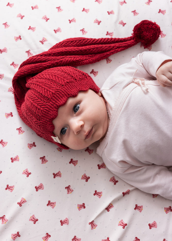 Baby wearing red knitted Santa hat with tassel and pink Christmas clothes