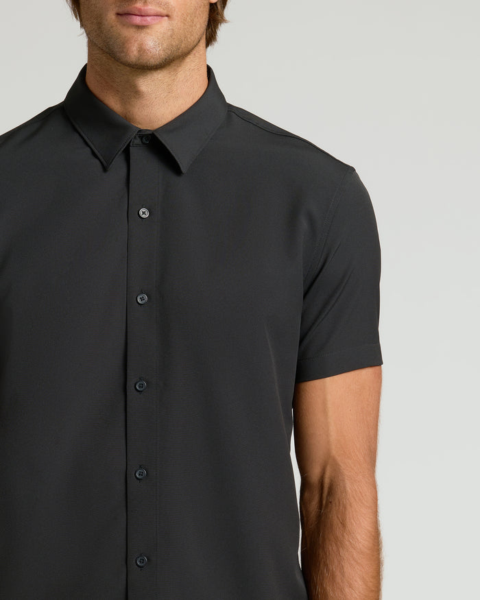 Person wearing All Black Short Sleeve Performance Dress Shirt, buttoned and collared.