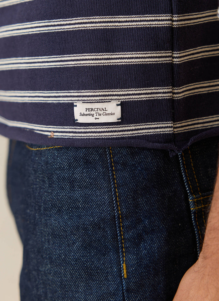 A close-up of the Percival navy stripe Breton t-shirt, showing the brand label near the raw hem.