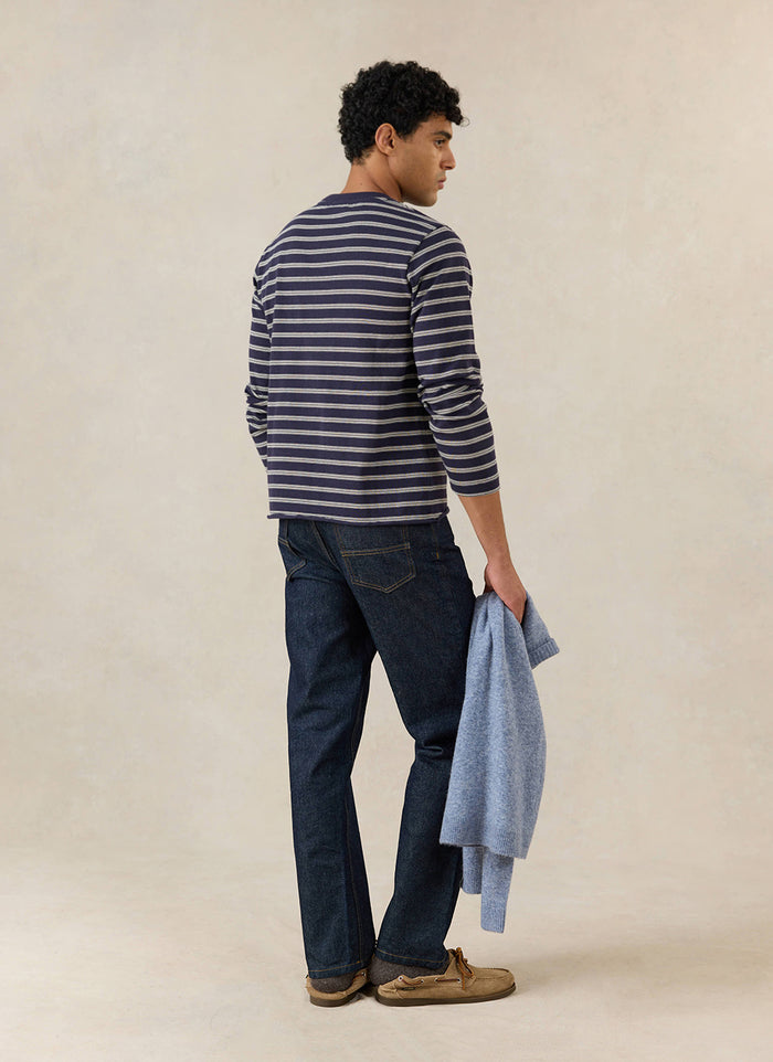 A model wears the navy stripe Percival Arlo long sleeve Breton T-shirt from behind, styled with dark jeans and shoes.
