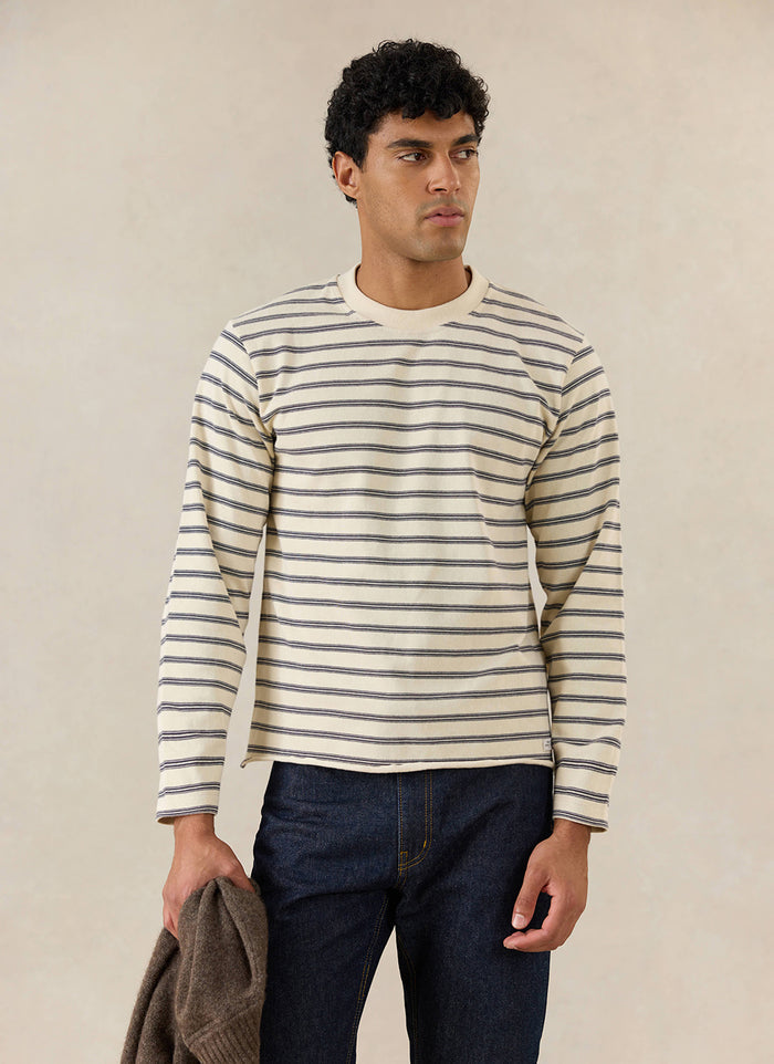 A model wears the white stripe Arlo long-sleeve Breton T-shirt from Percival, styled with dark jeans.
