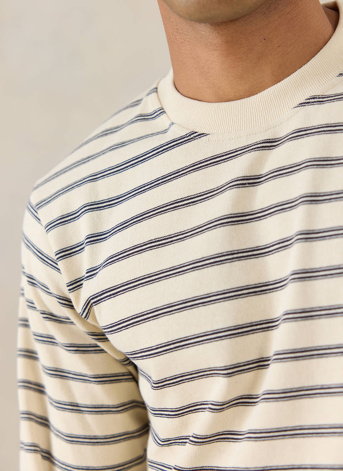 A close-up of a model wearing the white stripe Arlo Breton long-sleeve T-shirt from Percival.
