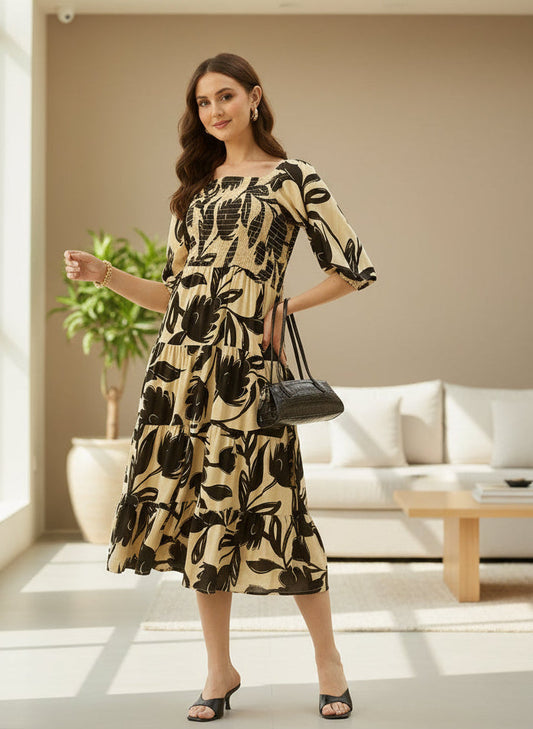 Woman in a floral dress standing in a modern living room. Black Floral Printed Smocked Tiered Dress, midi dress, dress, women’s western wear, party wear dress, casual wear dress