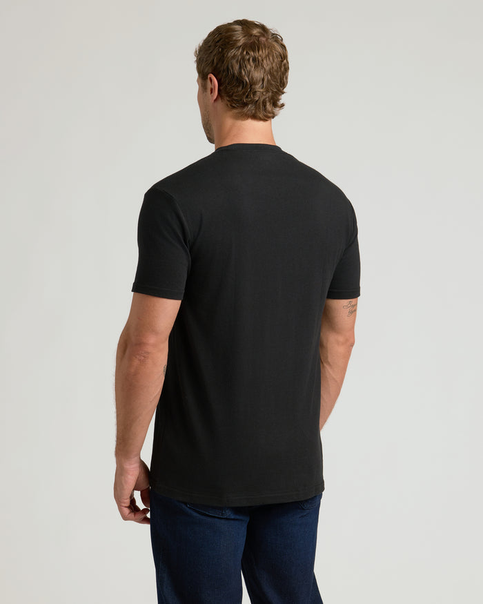 Man wearing Black Pocket Crew Tee and dark blue jeans, back view.