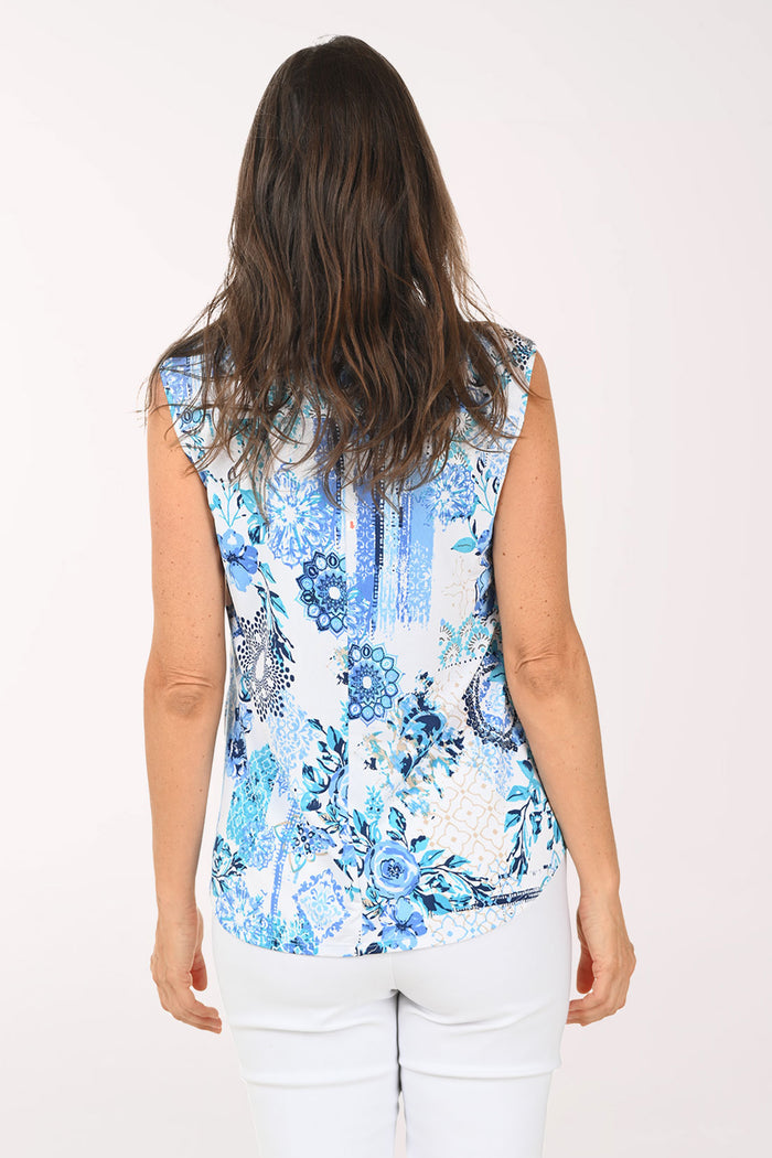 Woman wearing a sleeveless blue floral top on a white background