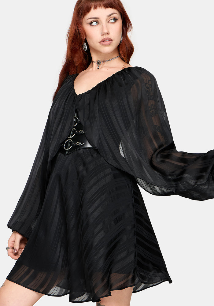 Woman wearing a black dress with sheer sleeves on a white background