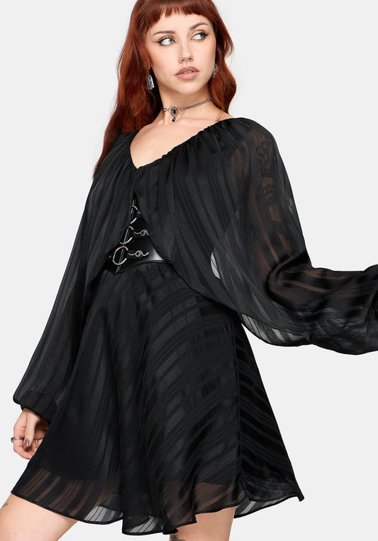 Woman wearing a black dress with sheer sleeves on a white background