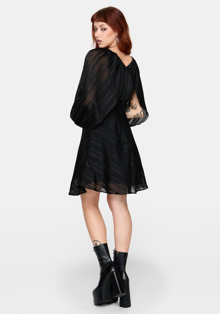 Woman wearing a black dress with sheer sleeves on a white background