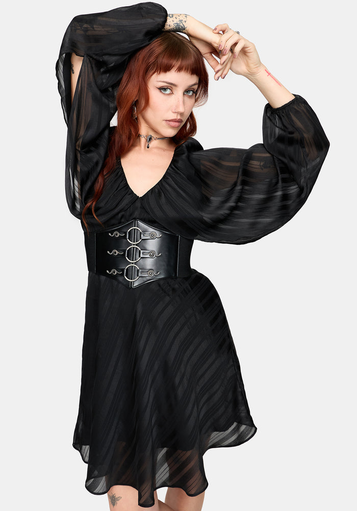 Woman wearing a black dress with a corset-style waist belt on a white background