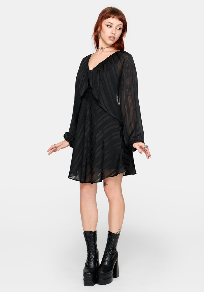 Woman wearing a black dress with sheer sleeves on a white background