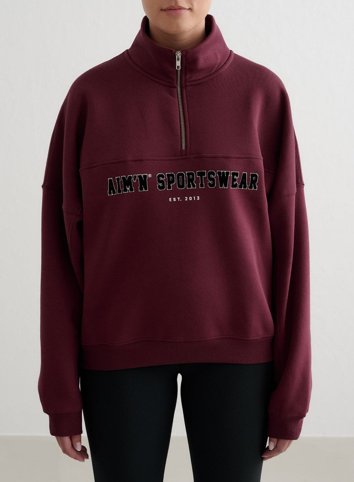 Cherry red Varsity Sweat Half Zip featuring a stand collar and aim'n sportswear embroidery.