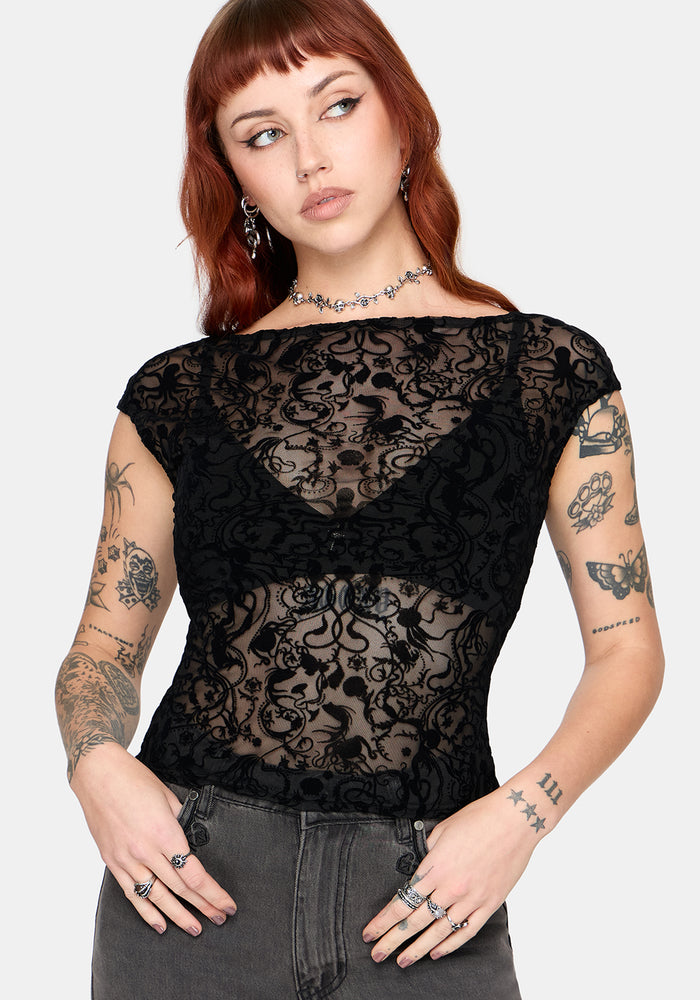 Woman wearing a sheer black lace top with short sleeves against a white background