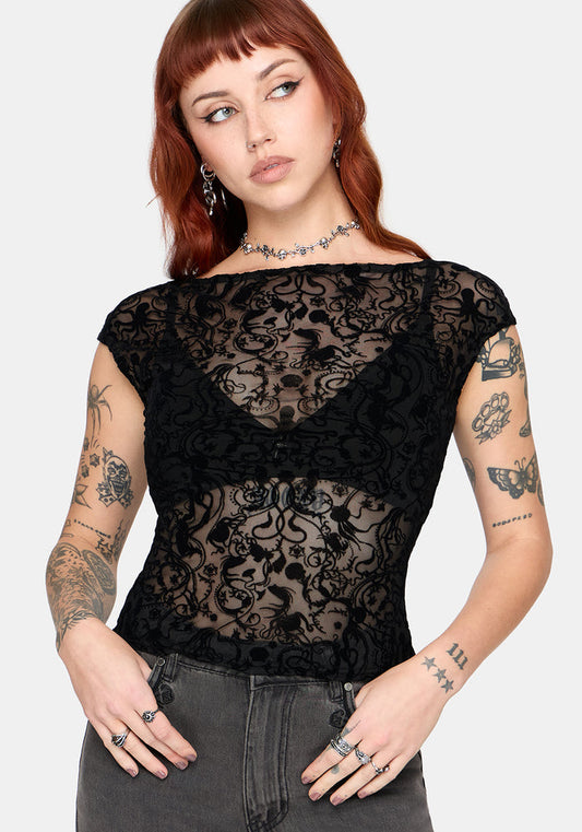 Woman wearing a sheer black lace top with short sleeves against a white background