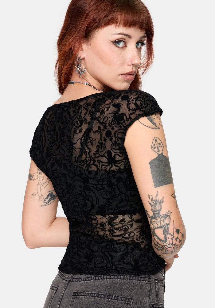 Woman wearing a sheer black lace top  against a white background