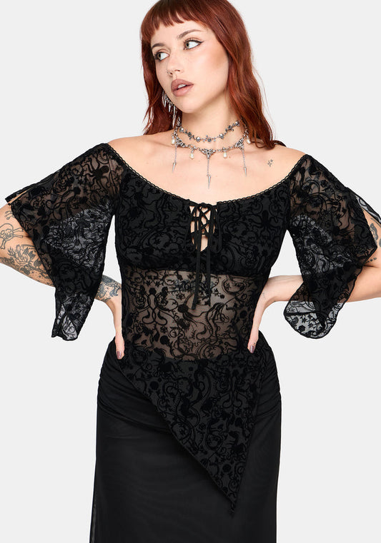 Woman wearing a black lace top with flared 3/4 sleeves and sheer panels on a white background