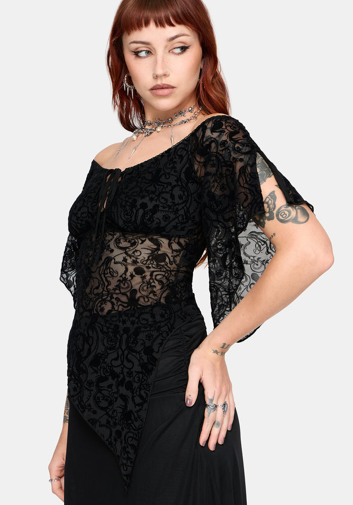 Woman wearing a black lace flared sleeve top against a white background