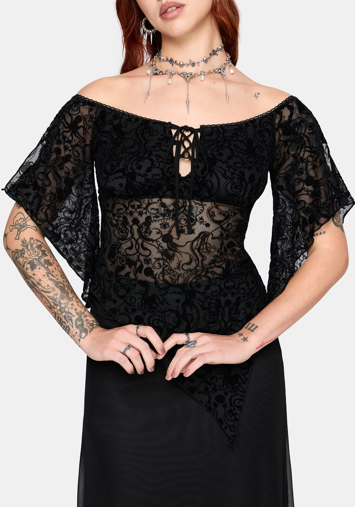 Woman wearing a black lace top with sheer sleeves on a white background