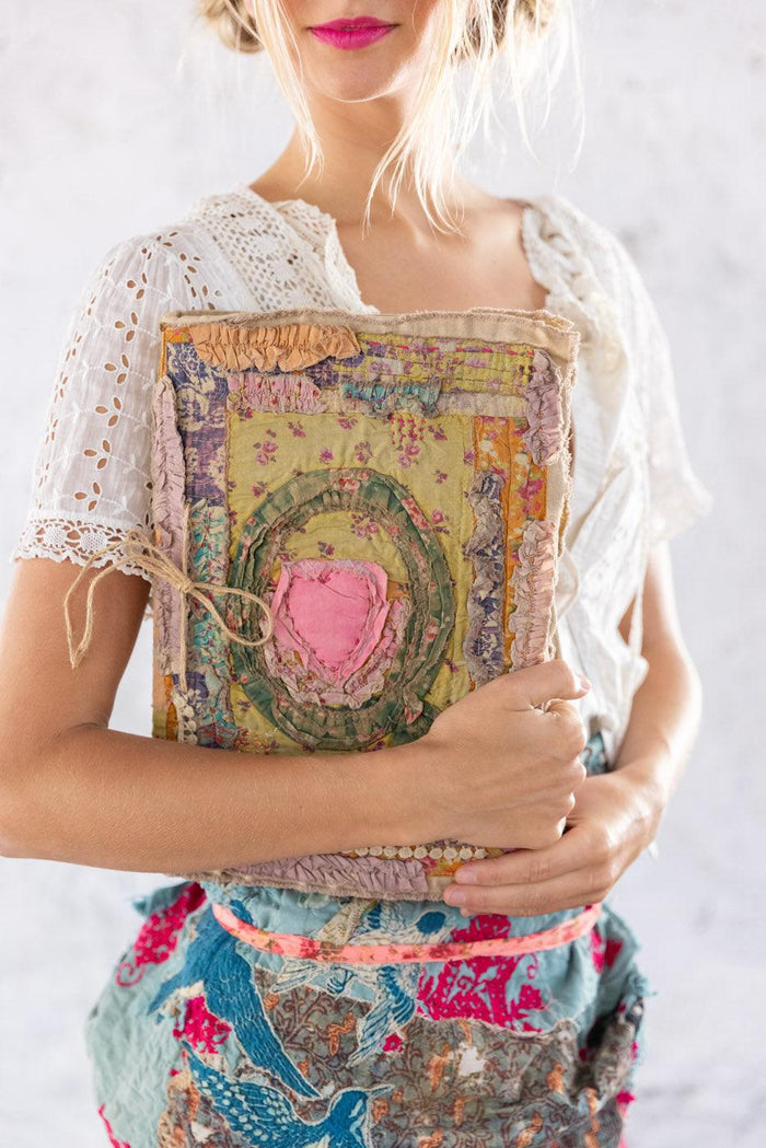 Woman in Magnolia Pearl vintage lace top and colorful artisan skirt holding whimsical handmade textile book