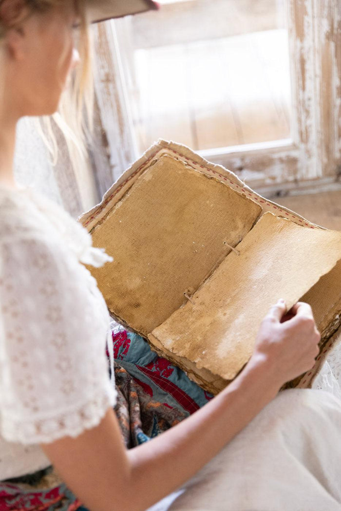Woman in Magnolia Pearl artisan vintage dress reading handmade aged book by rustic window