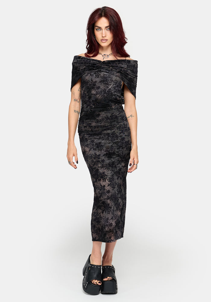 A woman modeling an off-the-shoulder patterned midi dress with a textured, slightly sheer floral lace-like pattern, paired with black platform shoes, against a light gray studio background.