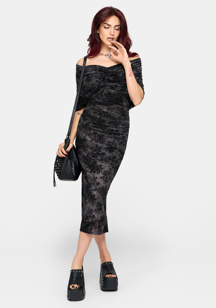 A woman modeling an off-the-shoulder black lace midi dress with ruching, paired with black platform loafers and a black studded shoulder bag, against a light gray studio background.
