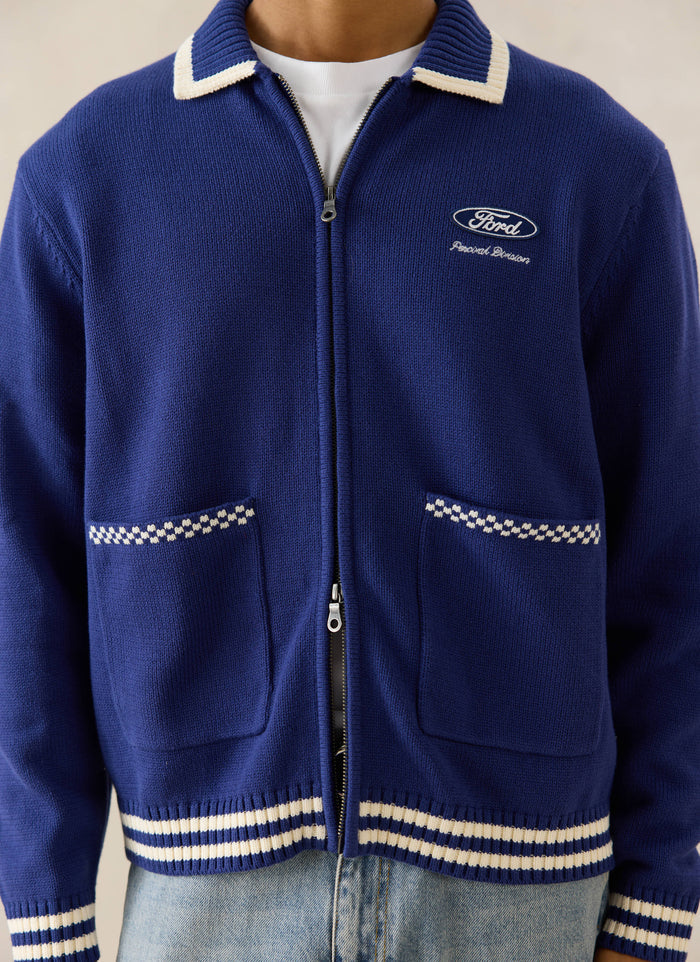 Cobalt blue Gardner Knitted Zip Cardigan from Ford x Percival, with checkered pocket trims and light-wash denim jeans.