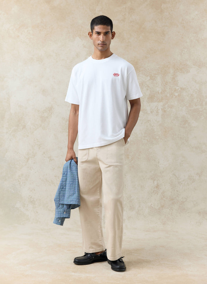 A model wears the white Percival Gordon Oversized T-Shirt in organic cotton with beige trousers and black loafers.
