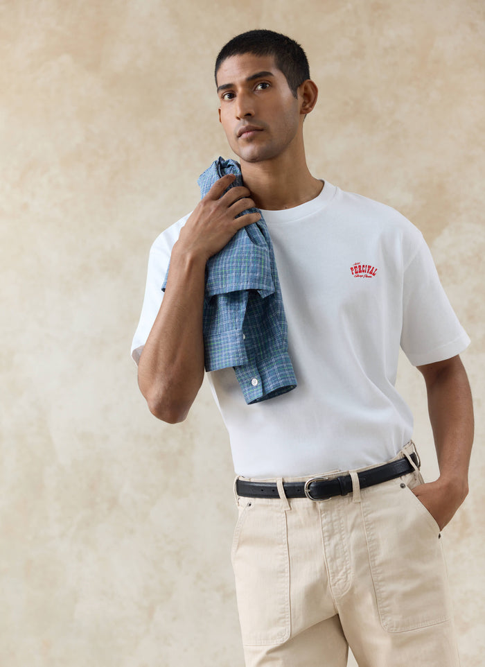 White Percival Gordon Oversized T-Shirt in organic cotton with a red chest print, styled with a blue checked shirt.