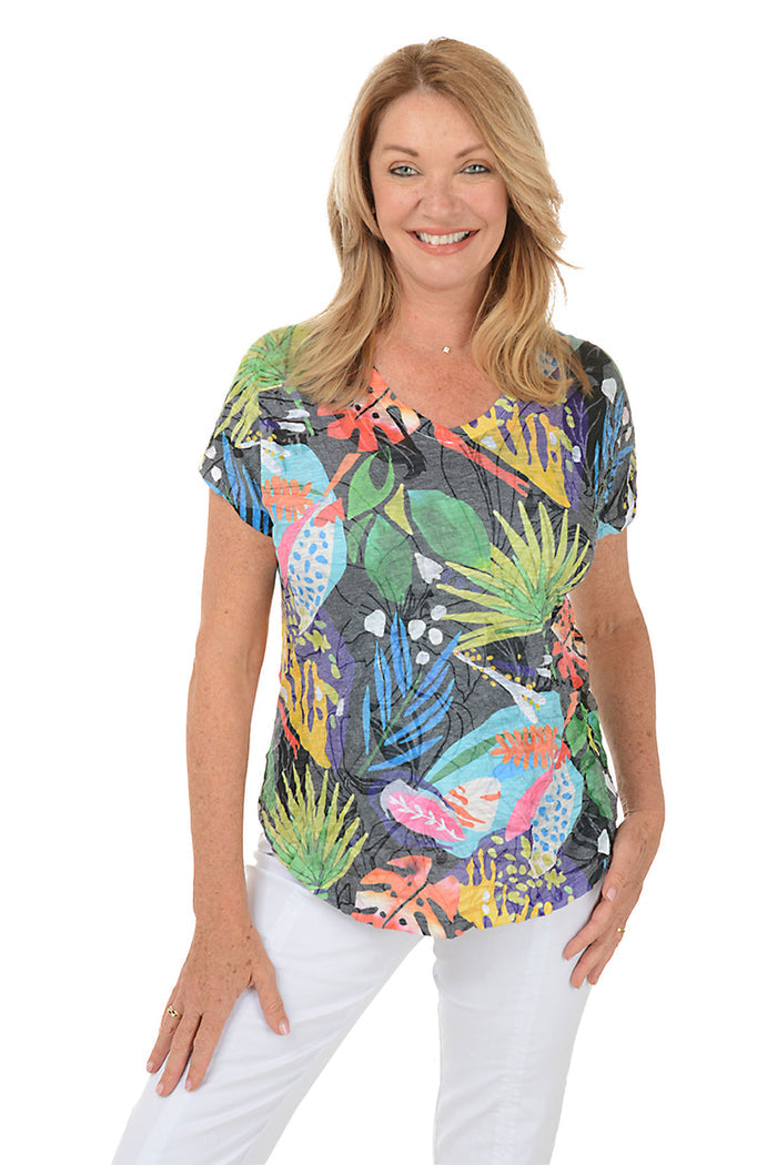 A woman wearing a multi colored tropical print short sleeve top.