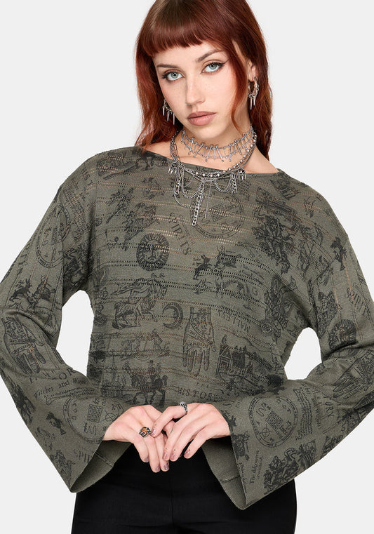 Woman wearing a patterned green jumper and black pants against a plain background