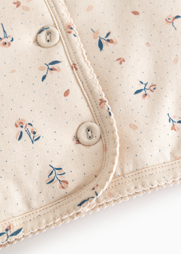 Detalje: knap og kant i babyjakke i lys beige med små blomster
