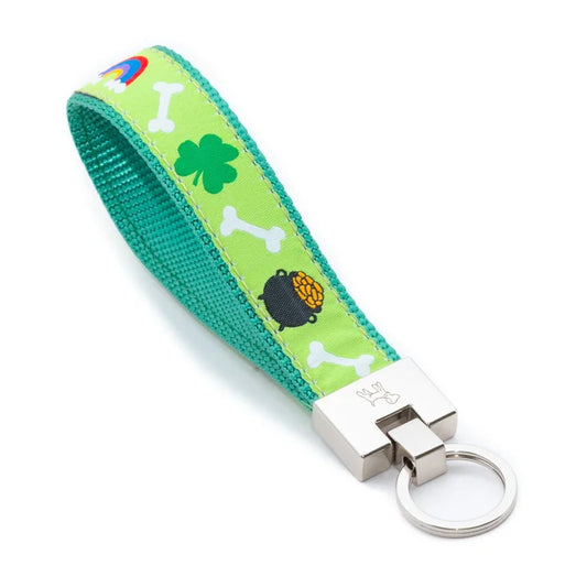 Keychain with green strap featuring shamrock, bones, and pot of gold designs on a white background.