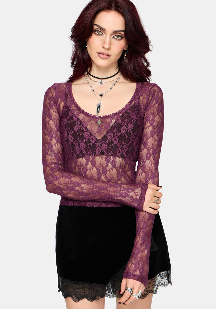 Woman wearing a sheer purple lace top with a black skirt on a white background