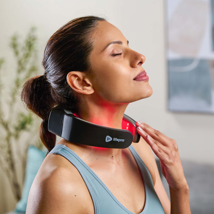 Woman with her eyes closed wearing the LumiNova neck device, its red light glowing against her neck as she touches the band with one hand.