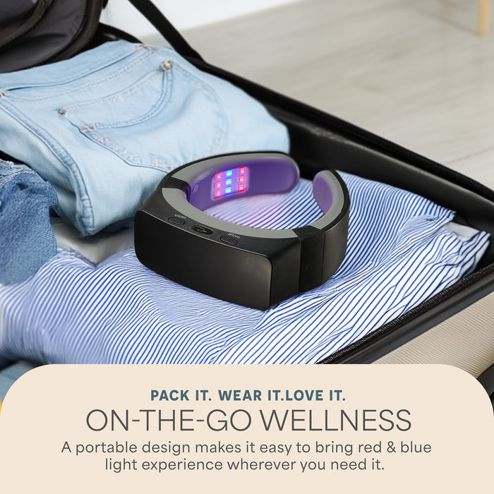 LumiNova neck device with its red and blue LEDs lit, resting open on folded clothes in a packed suitcase, captioned Pack It. Wear It. Love It. On-The-Go Wellness.