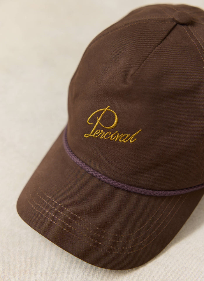 Close-up of the espresso brown Percival Luther Soft Trucker Cap in brushed cotton with gold script embroidery.