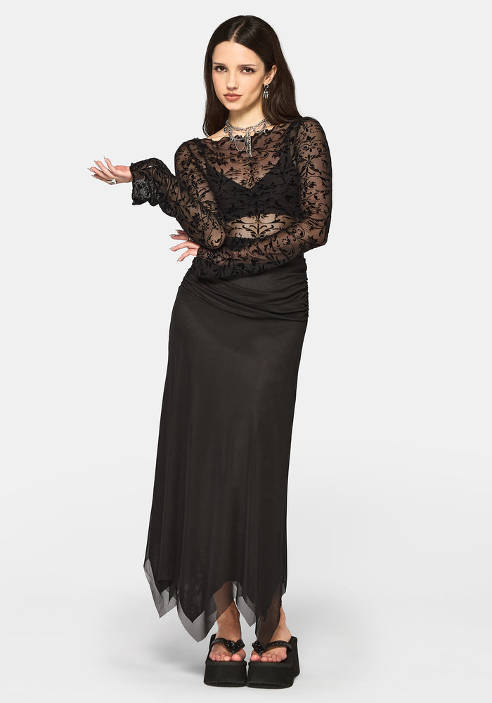 Woman wearing a black long sleeve top and black maxi skirt on a white background