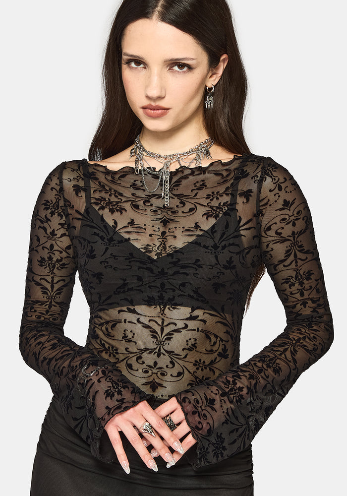 Woman wearing a black mesh long-sleeve top against a white background