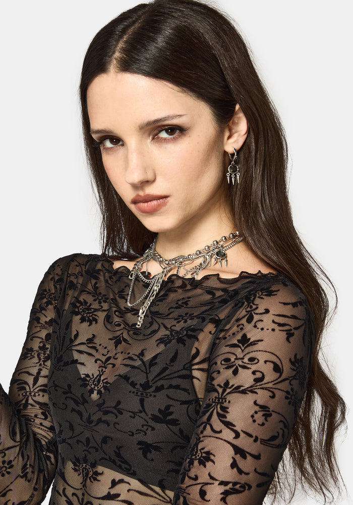 Woman wearing a black mesh top with jewelry on a white background