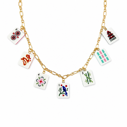 Gold necklace with playing card charm charms on a white background