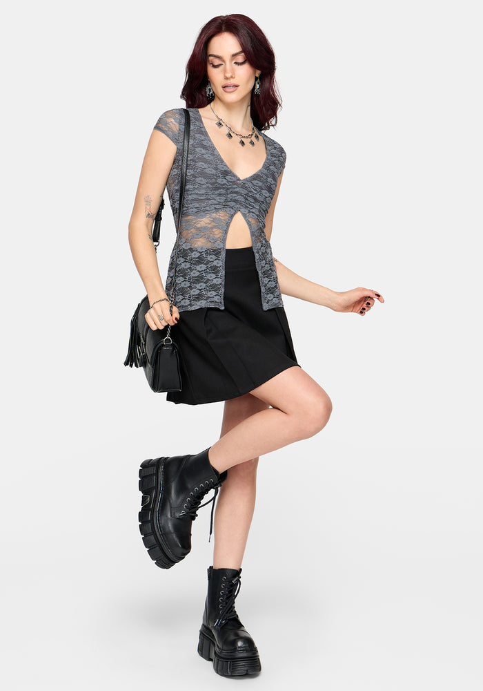 Woman wearing a gray lace top with an open midriff design and black skirt on a white background